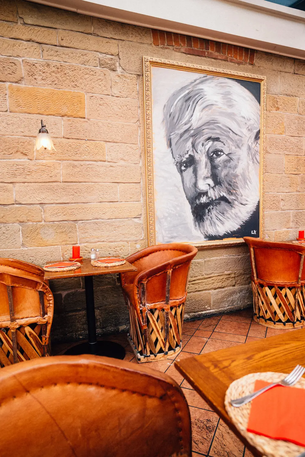 Blick auf Gastronomie Interieur, Stühle und Tische. An der Wand: ein Bild von Hemingway.