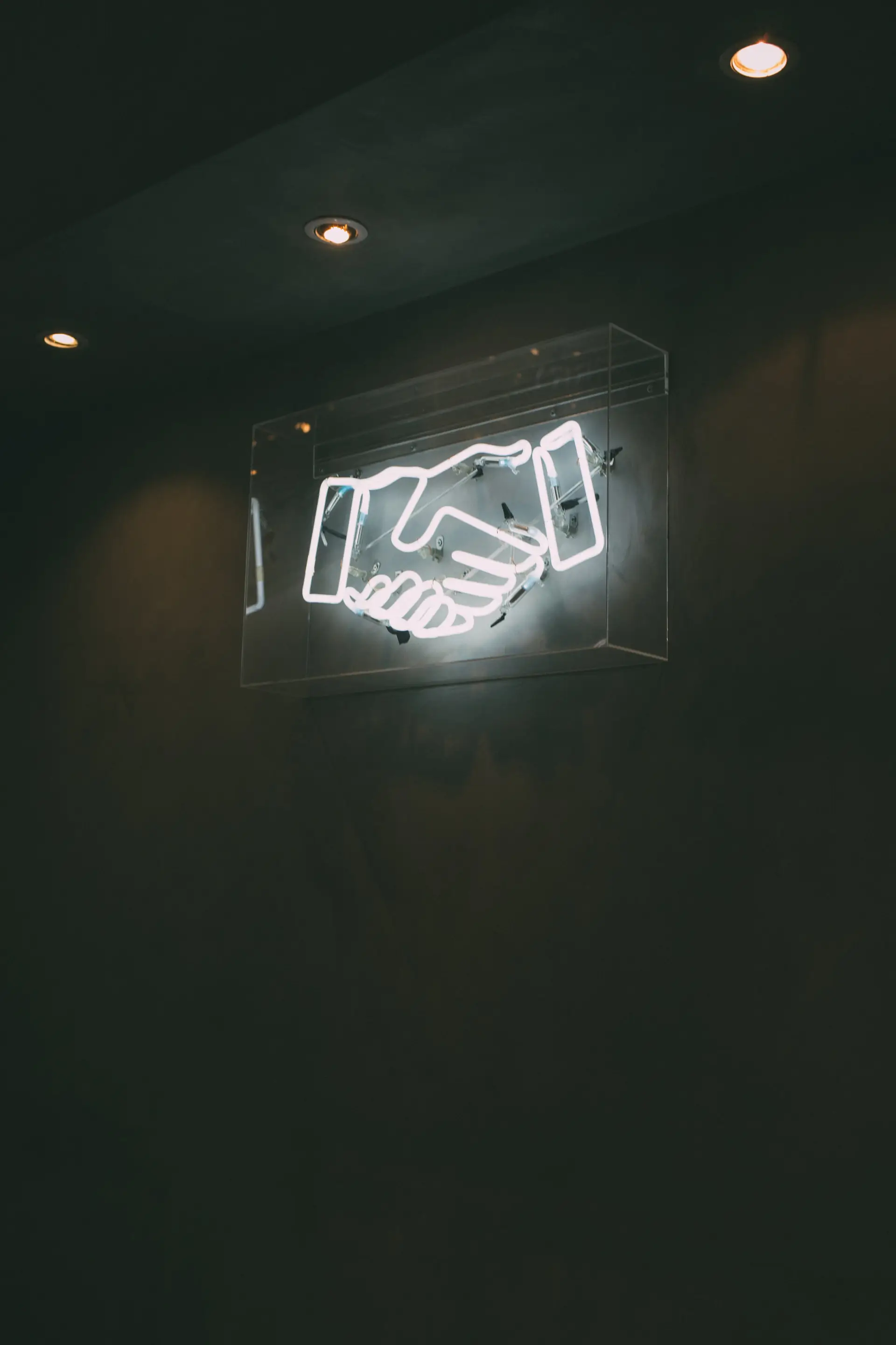 Bild von einem Neon-Zeichen von zwei sich gegenseitig schüttelnden Händen